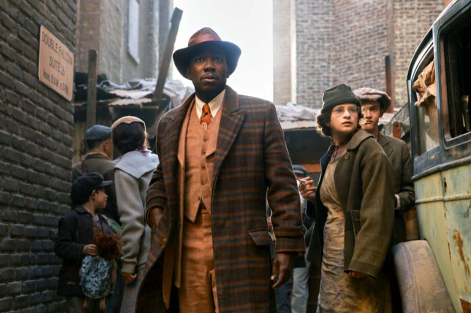 Group of people in vintage clothing in an alleyway with old vehicles.